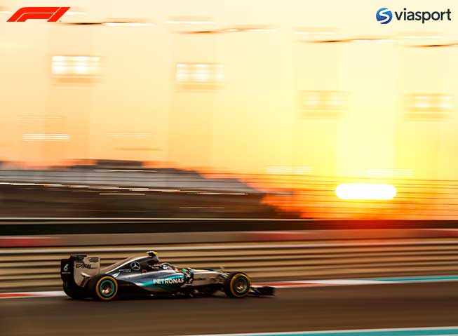 Formel 1-bil i løp, susende forbi i solnedgangsbelysning.