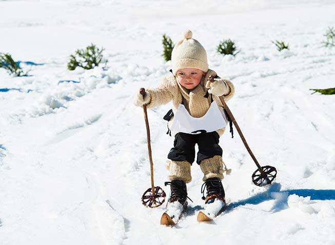 Liten gutt med gammeldags skiutstyr og deltakervest går langrenn